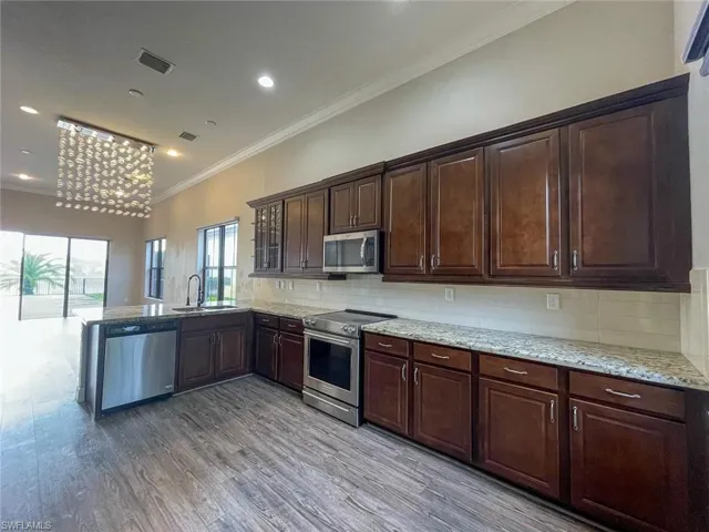 Kitchen featuring light hardwood / wood-style floors, sink, appliances with stainless steel finishes, tasteful backsplash, and dark brown cabinetry