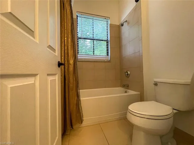 Bathroom with tile patterned flooring, shower / bath combo with shower curtain, and toilet