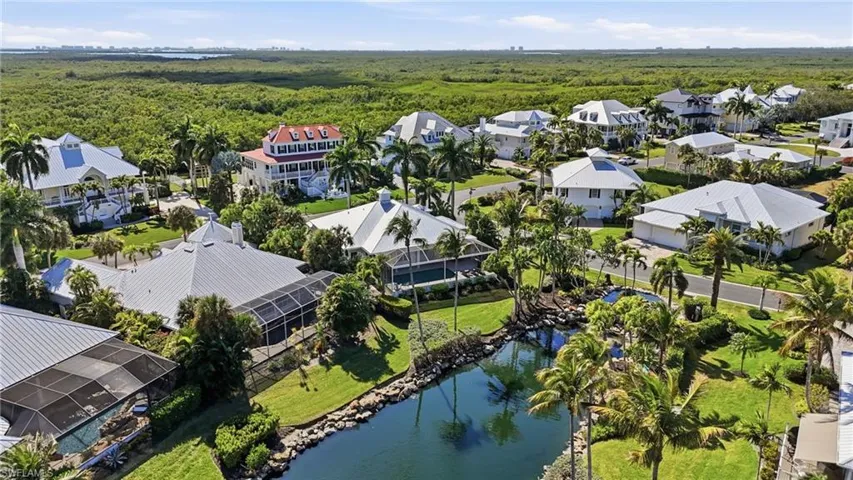 Aerial perspective of suburban area featuring a forest and a large body of water