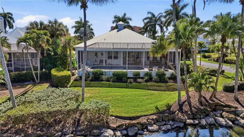 Rear view of property featuring a standing seam roof, a sunroom, a yard, and an outdoor pool