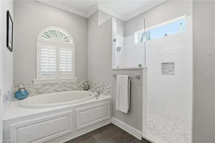 Bathroom featuring a garden tub, walk in shower, and ornamental molding