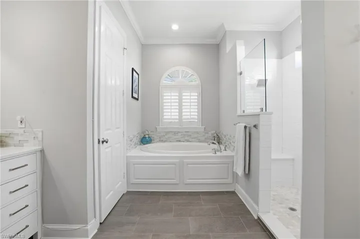 Full bathroom with a garden tub, ornamental molding, a walk in shower, and vanity