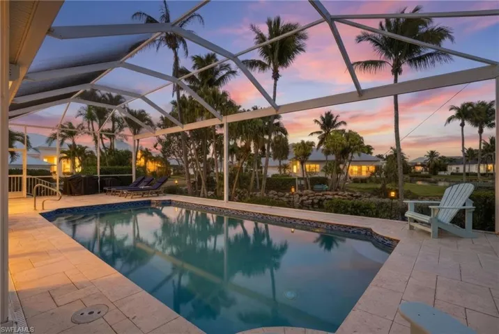 Pool at dusk featuring an outdoor pool, glass enclosure, and a sunroom