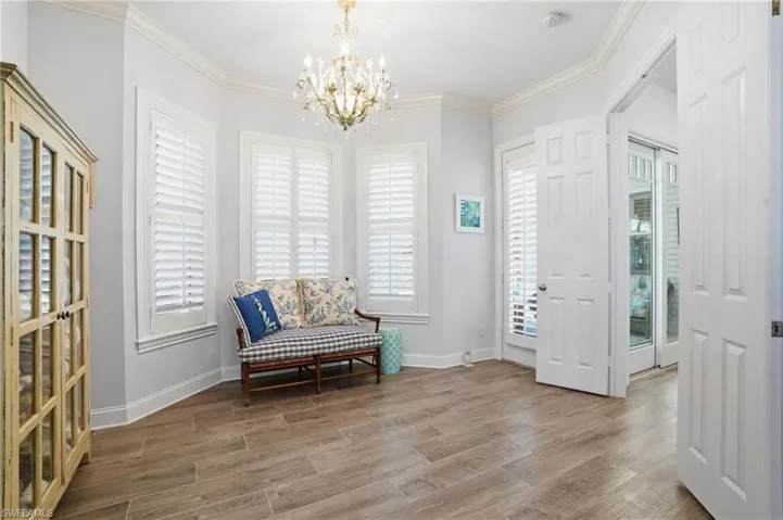 Sitting room featuring suspended lighting, wood finish floors, and ornamental molding