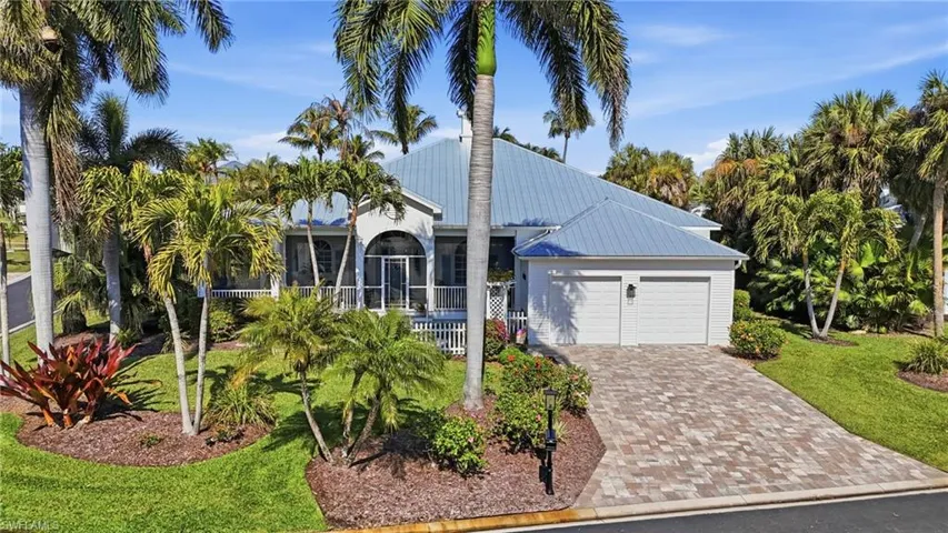 View of front of house with a front yard, driveway, a metal roof, and an attached garage