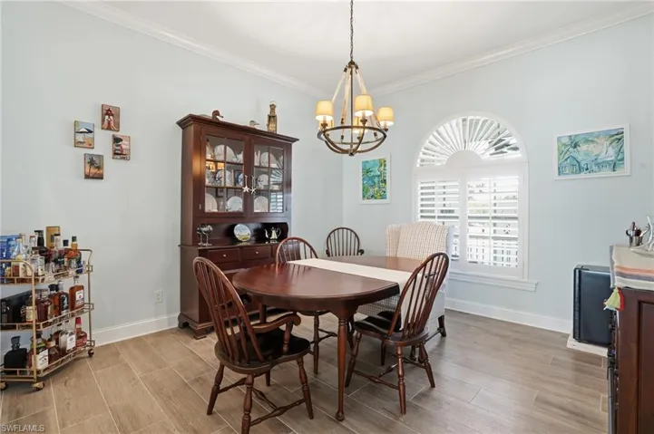 Dining room featuring wood finish floors, crown molding, and hanging lights