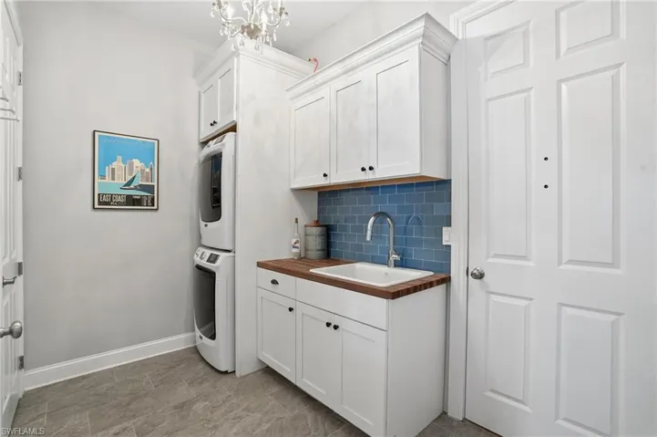 Laundry area with stacked washer / drying machine, cabinet space, and suspended lighting