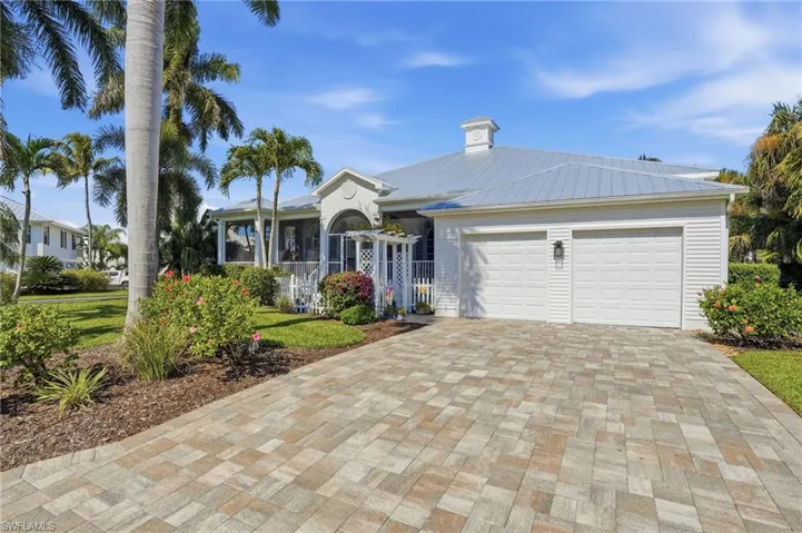 Ranch-style home featuring driveway, a metal roof, an attached garage, a chimney, and a front yard