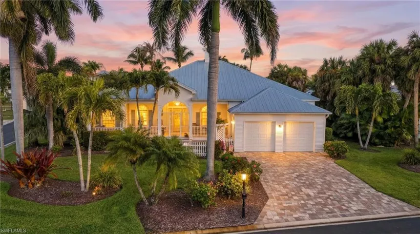View of front of home featuring a metal roof, driveway, a front yard, and a garage