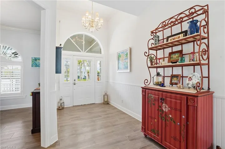 Entrance foyer featuring wainscoting, light wood-style floors, hanging lights, healthy amount of natural light, and ornamental molding