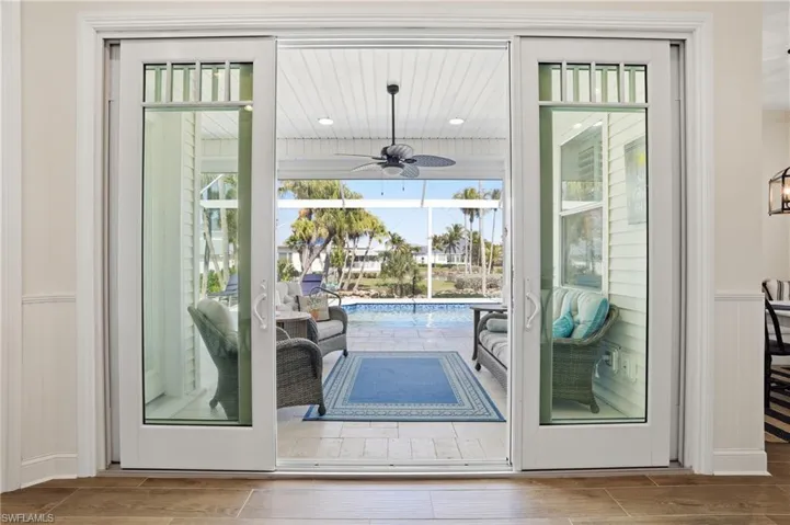 Doorway to outside featuring a wainscoted wall, ceiling fan, and wood finish floors