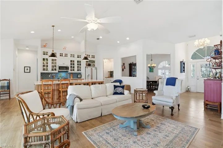 Living room featuring light wood-type flooring, lofted ceiling, a ceiling fan, and hanging lights