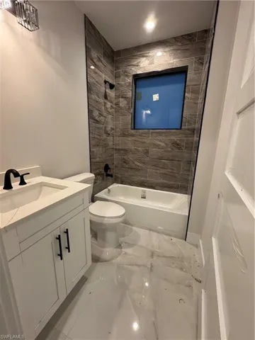Bathroom with vanity, washtub / shower combination, and light marble finish floors