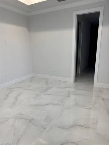Empty room featuring crown molding and light marble finish flooring