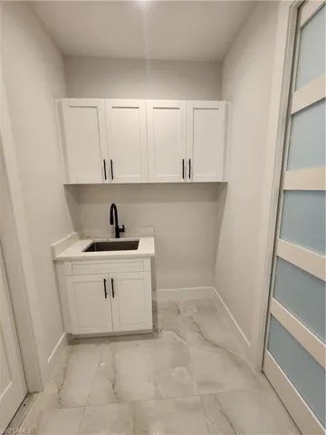 Laundry area with baseboards and light marble finish flooring