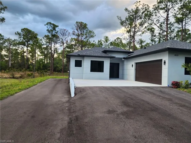View of front of house with driveway, stucco siding, a garage, and a shingled roof