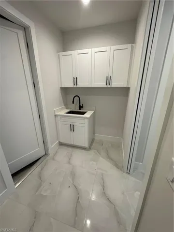 Laundry area featuring light marble finish flooring and a sink