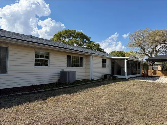 Rear view of house with a yard, a shingled roof, and a sunroom