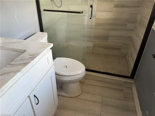 Full bath featuring vanity, a stall shower, and light wood-type flooring