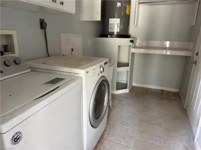 Laundry room featuring cabinet space, water heater, separate washer and dryer, and light tile patterned floors
