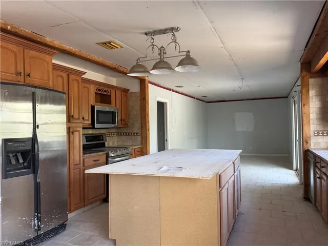 Kitchen with stainless steel appliances, a center island, wood finish cabinetry, and backsplash