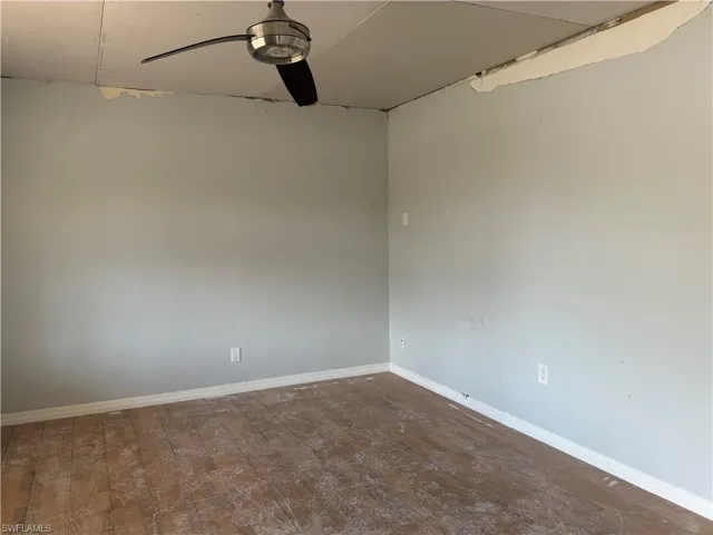 Empty room featuring ceiling fan and dark wood-type flooring