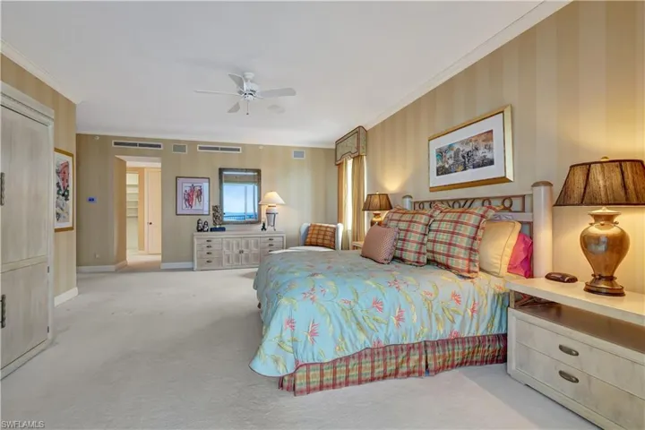 Carpeted bedroom with ceiling fan and ornamental molding