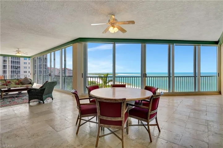 Sunroom / solarium with ceiling fan, plenty of natural light, and a water view