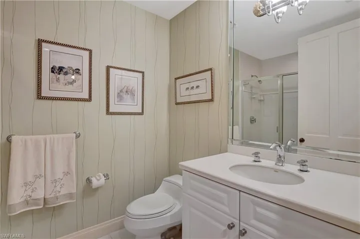 Bathroom with wood walls, a shower with door, toilet, and vanity