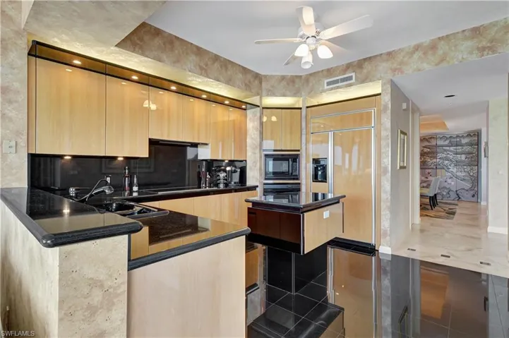 Kitchen with sink, black microwave, kitchen peninsula, backsplash, and ceiling fan