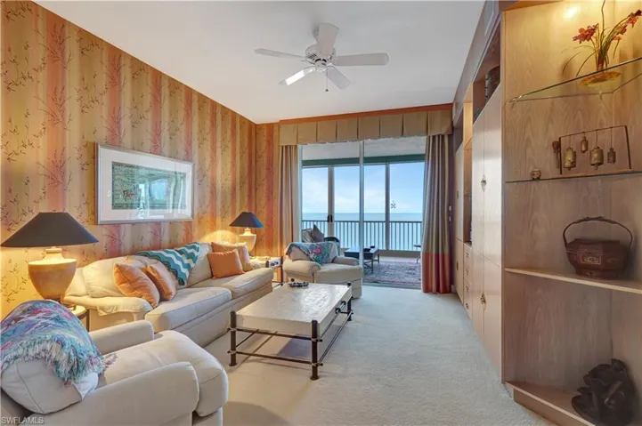 Living room with light colored carpet, a water view, and ceiling fan