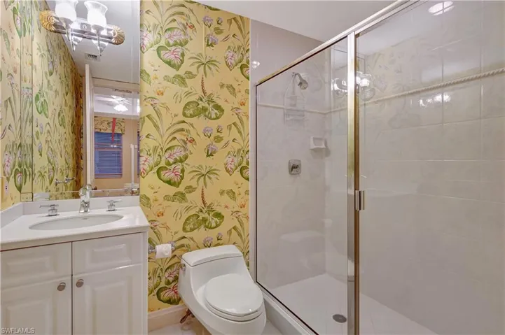 Bathroom featuring toilet, walk in shower, and vanity