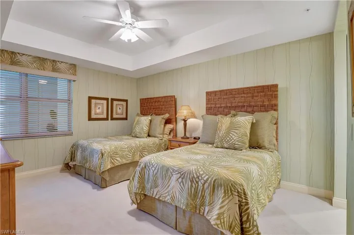 Bedroom featuring light carpet, ceiling fan, and a raised ceiling