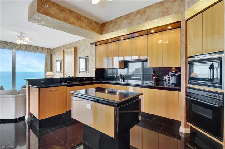 Kitchen with ceiling fan, sink, a water view, a center island, and black appliances