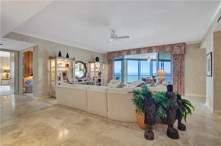 Living room featuring ceiling fan, a water view, and ornamental molding