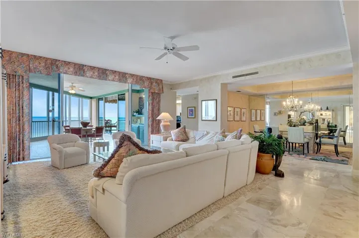 Living room featuring crown molding, plenty of natural light, ceiling fan with notable chandelier, and a water view