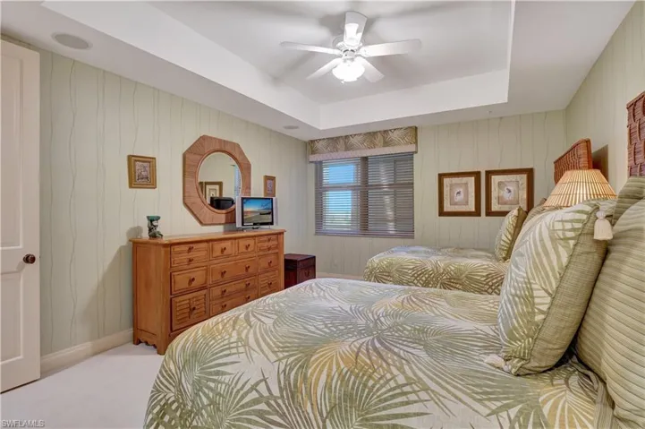 Bedroom featuring ceiling fan, light colored carpet, and a tray ceiling