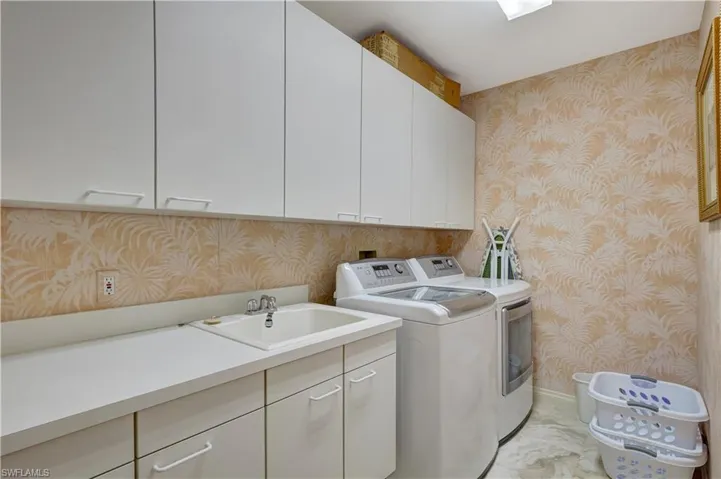 Laundry room with sink, cabinets, and washing machine and dryer