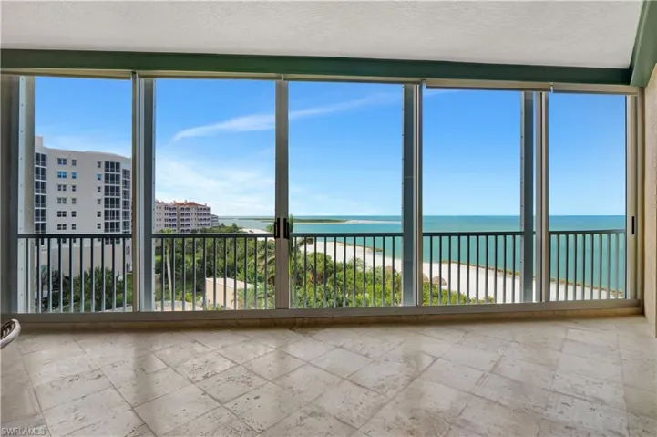 Unfurnished sunroom with a water view and a beach view