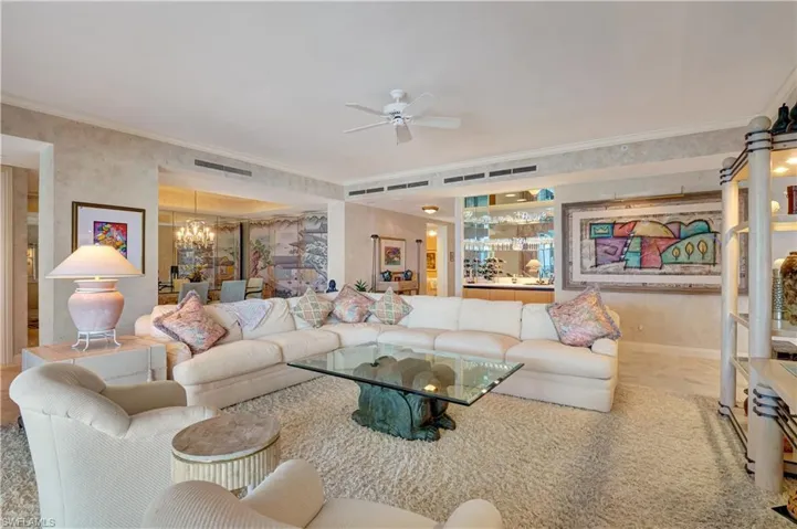 Living room with ceiling fan with notable chandelier and ornamental molding