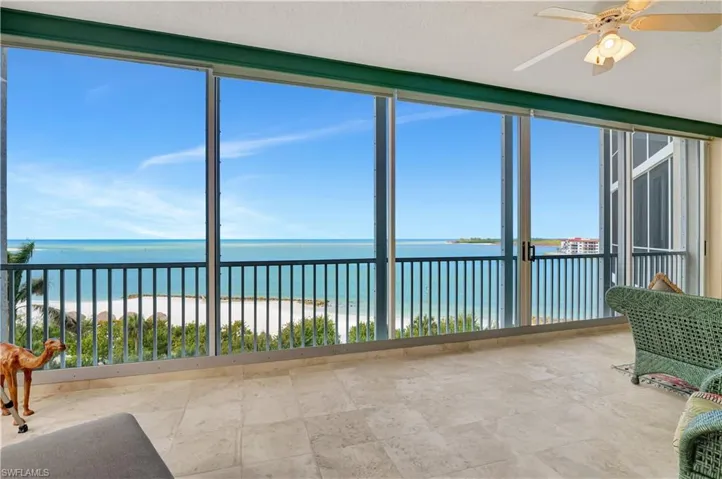 Unfurnished sunroom with a beach view, ceiling fan, a wealth of natural light, and a water view