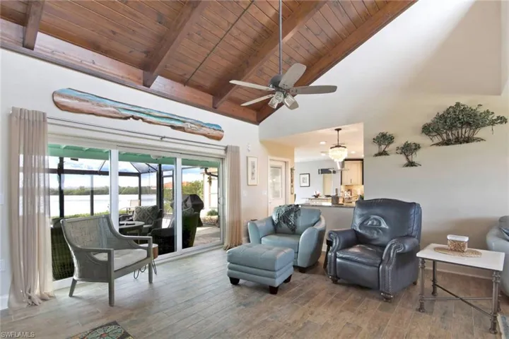 Living area featuring high vaulted ceiling, a wooden ceiling with exposed beams,  ceiling fan, and a water view