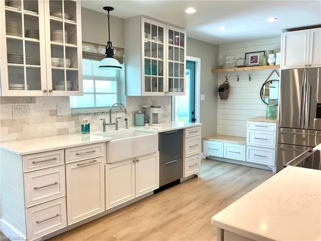 Kitchen with white cabinets, stainless steel fridge with ice dispenser, light stone counters, light wood-style flooring, and recessed lighting