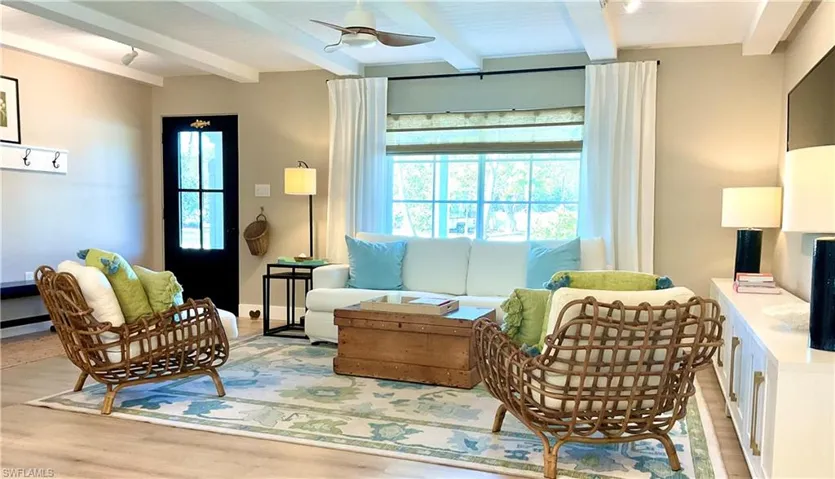 Living area with a ceiling fan, light wood-type flooring, and beam ceiling