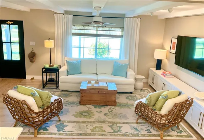 Living room with beamed ceiling, light wood-style floors, and a ceiling fan