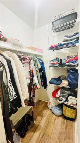 Walk in closet with hardwood / wood-style flooring