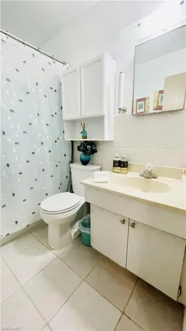Bathroom with tile flooring, backsplash, toilet, and vanity
