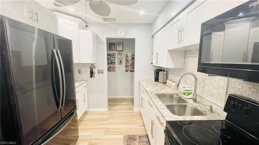 Kitchen with white cabinets, range with electric stovetop, backsplash, fridge, and ceiling fan