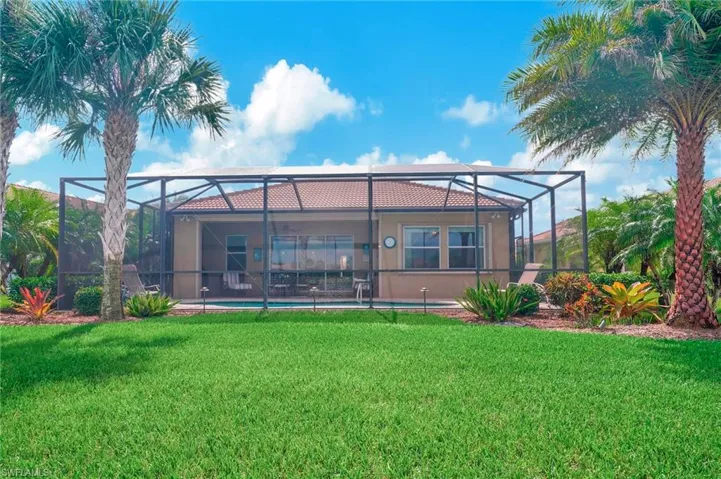Rear view of property featuring glass enclosure and a yard