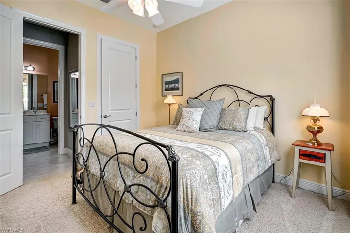 Bedroom with a closet, ceiling fan, connected bathroom, and light carpet